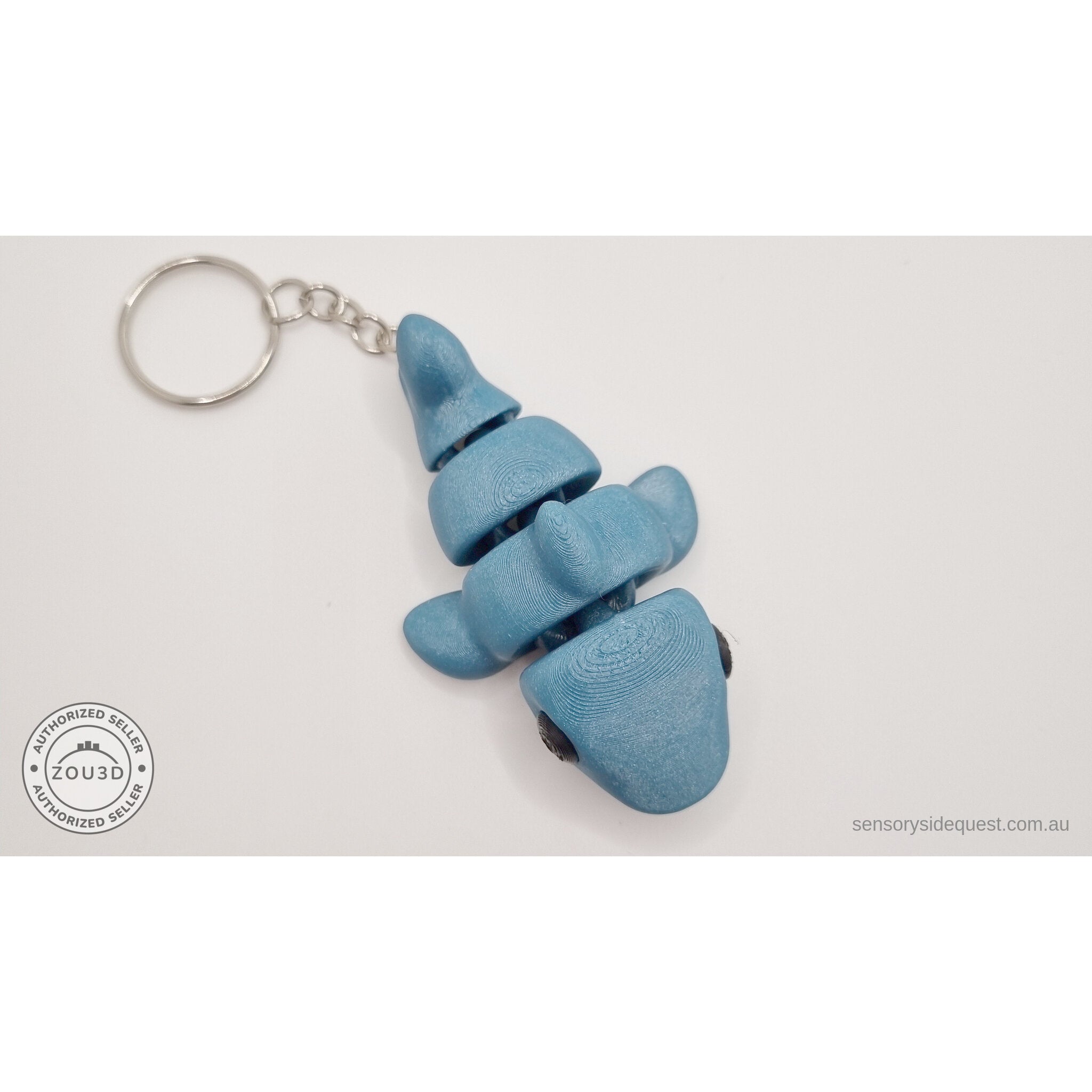 027-TNYSHK Tiny Shark keychain in gentian blue — upright dangling view under metallic lighting showing deep sapphire blue shimmer finish and segment detail — 3D printed articulated fidget toy by Sensory Sidequest