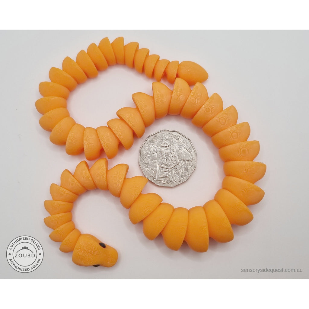 Orange 3D printed ball python fidget toy in S-curve pose beside Australian 50 cent coin — scale reference showing full body length