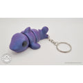 027-TNYSHK Tiny Shark keychain in crushed electric purple — 3/4 front view showing iridescent purple-to-blue shimmer, chibi face, dorsal fin, and keychain — 3D printed fidget toy by Sensory Sidequest