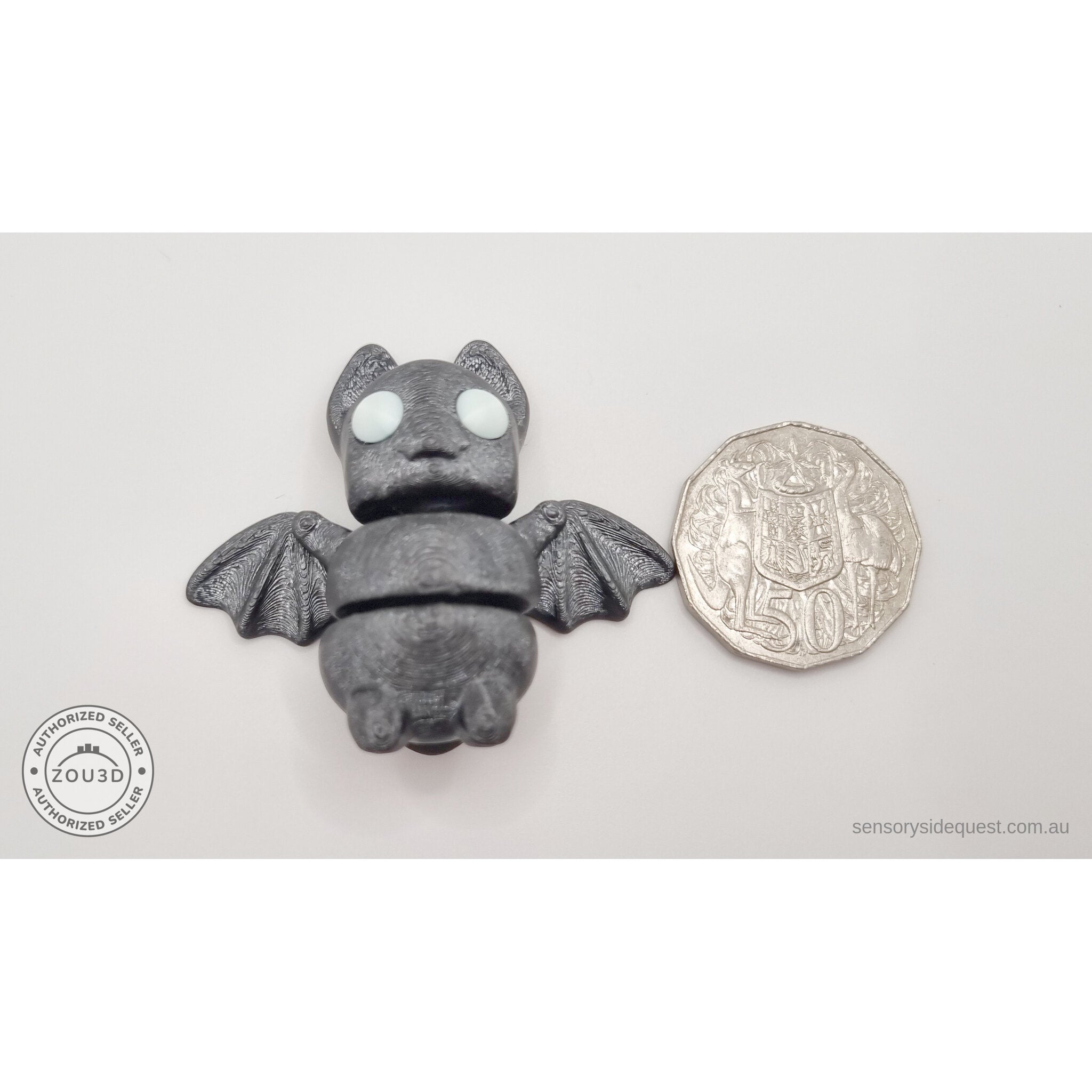 Tiny Bat with white eyes beside Australian 50 cent coin — scale reference