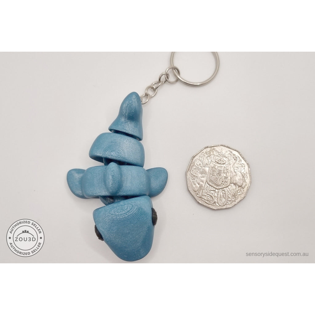 027-TNYSHK Tiny Shark keychain in gentian blue — overhead scale reference beside Australian 50 cent coin, matte teal-blue colourway under standard lighting — 3D printed articulated fidget toy by Sensory Sidequest