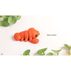 Baby Lobster articulated fidget toy — official Zou3D render, side profile with plant lifestyle props, orange colourway