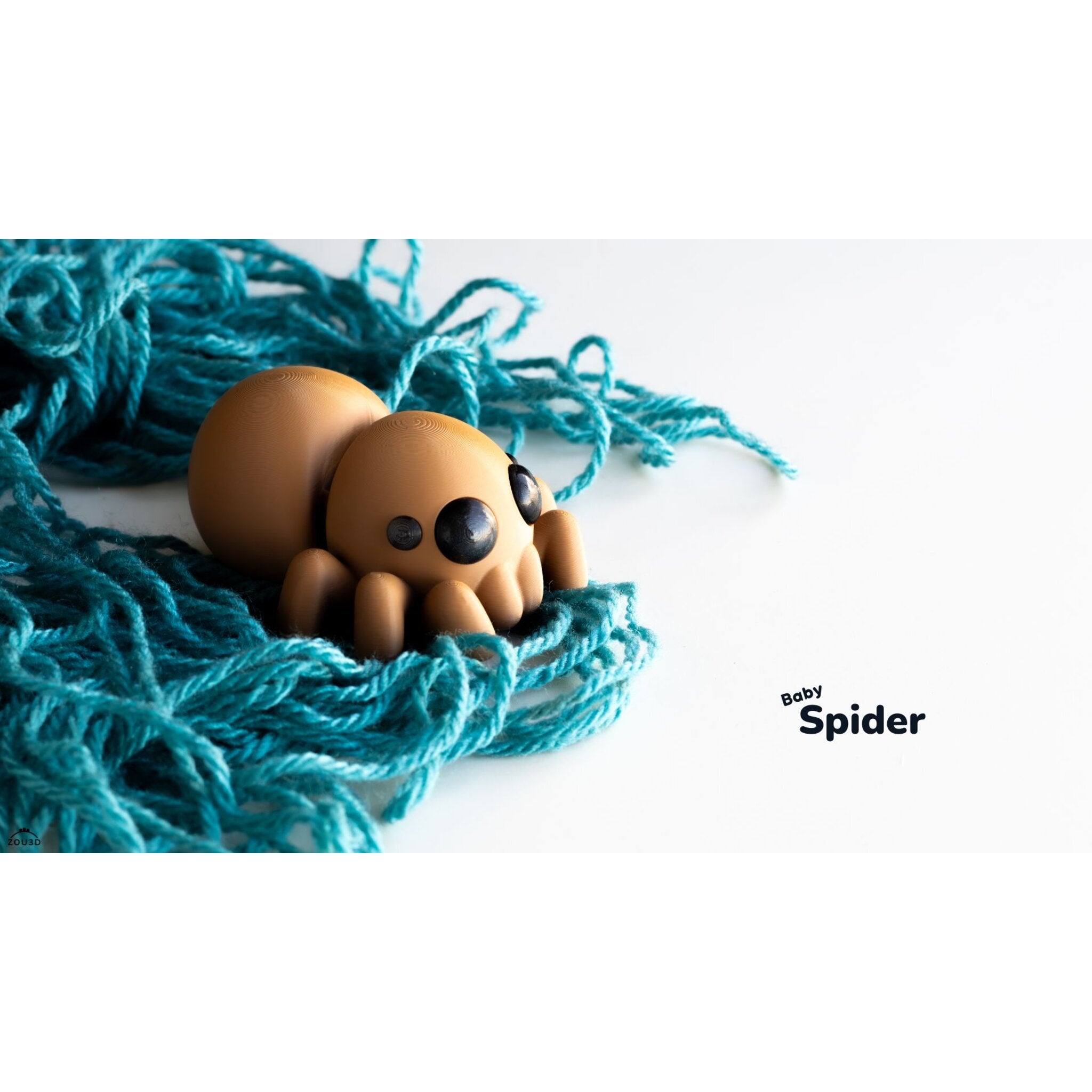 Zou3D Baby Spider articulated toy peeking over teal yarn — side-angle lifestyle shot showing compact palm-sized form