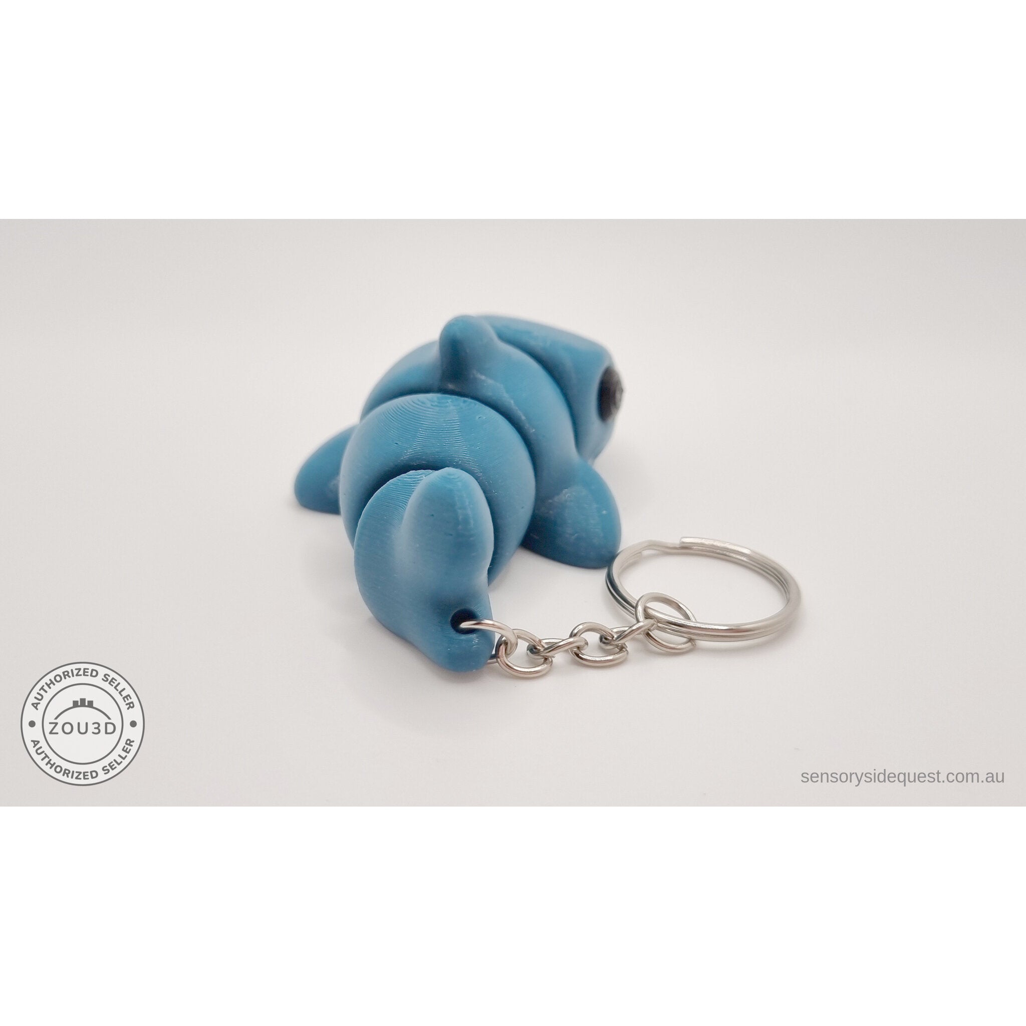 027-TNYSHK Tiny Shark keychain in gentian blue — side view with body slightly curved, showing segment articulation and keychain ring — 3D printed articulated fidget toy by Sensory Sidequest