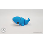 Baby Blue Whale articulated toy — close 3/4 front view showing large eye, white belly panel and blue body detail, own photo by Sensory Sidequest