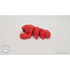 Baby Lobster articulated fidget toy in red silk — side profile view showing segmented body, claw, and tail — Sensory Sidequest