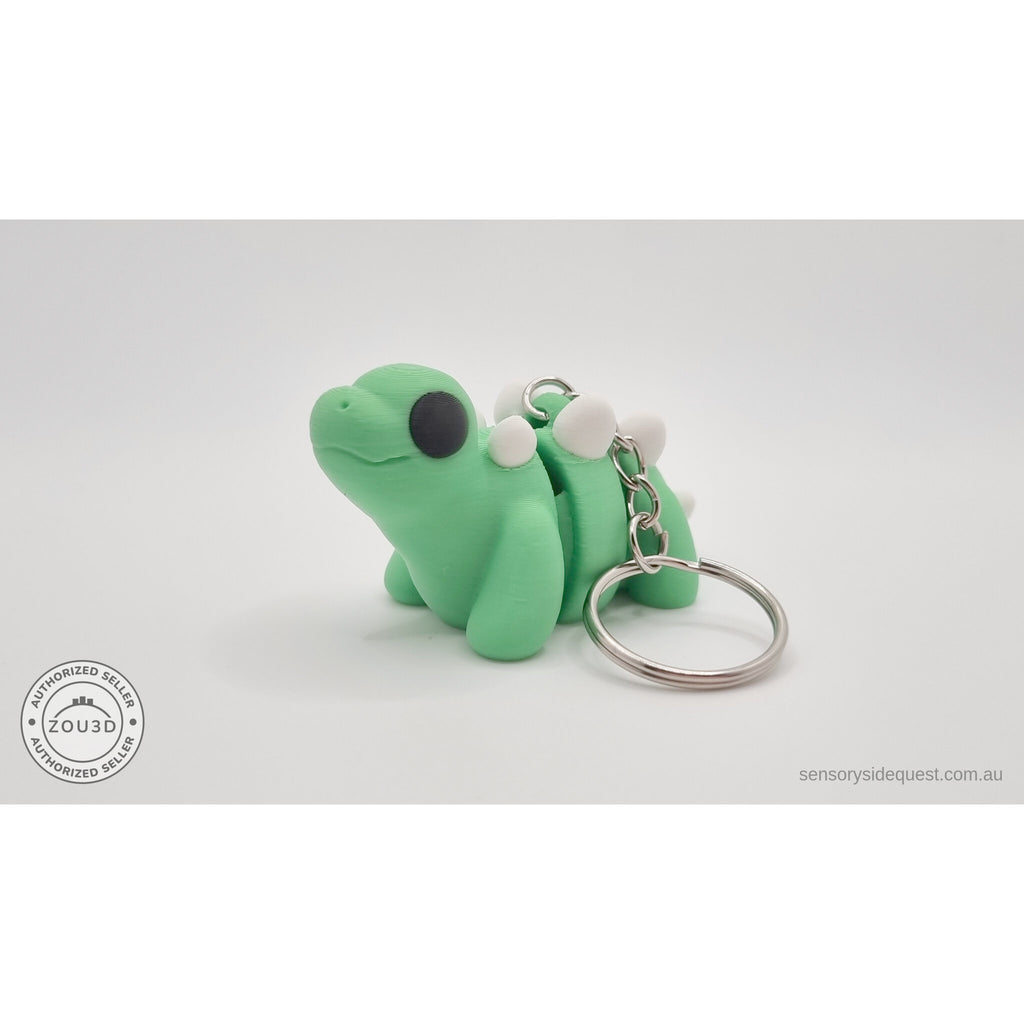 Baby Stegosaurus keychain — three-quarter front view showing ring and chain hardware