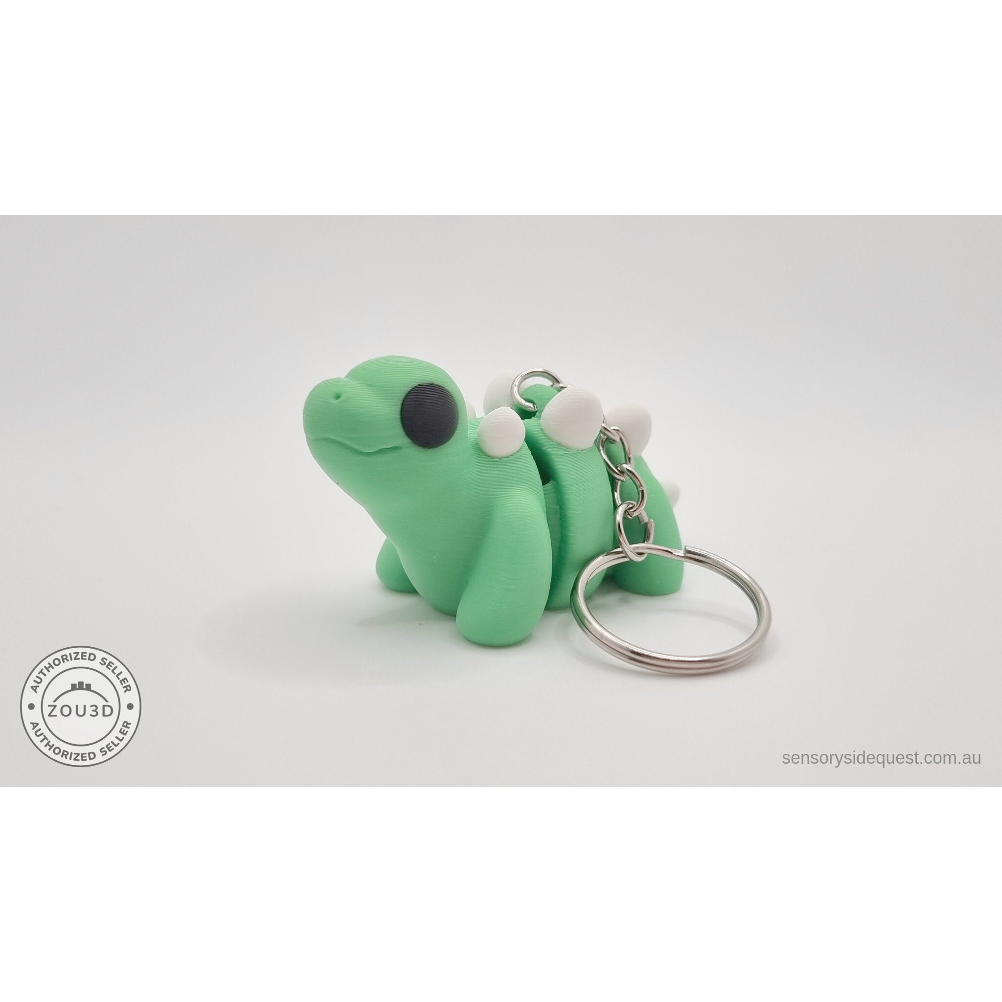 Baby Stegosaurus keychain — three-quarter front view showing ring and chain hardware